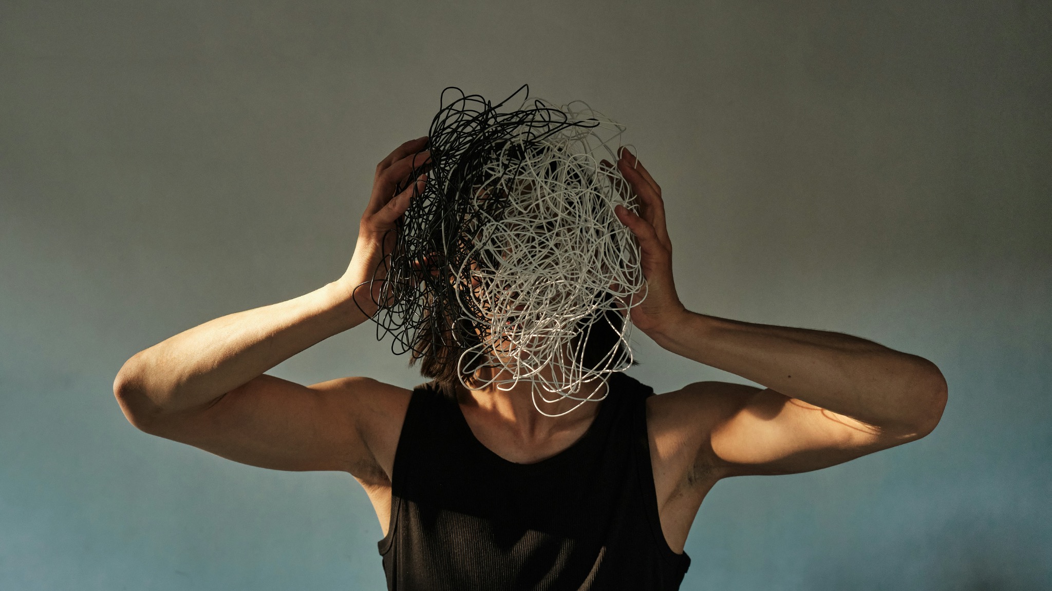 A person holding a tangled mass of threads in front of their face
